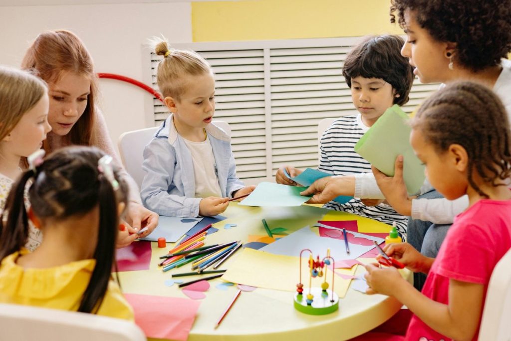 Cores na escola professores e alunos numa mesa redonda pintando