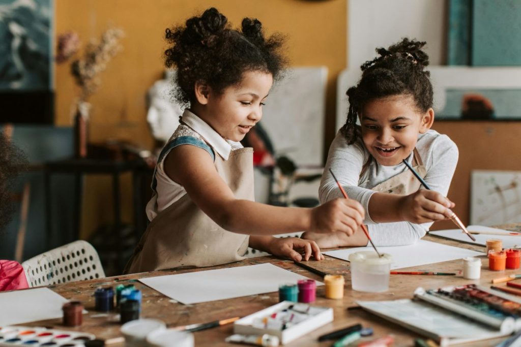 Duas meninas feliz pintando com tinta e pincel