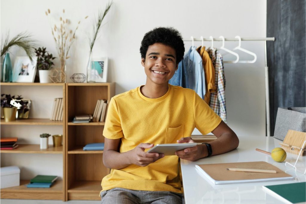 Ferramentas e aplicações menino segurando um tablet e estudando no seu quarto